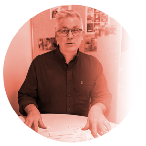 Man in glasses discussing at a table with papers in a creative workspace.
